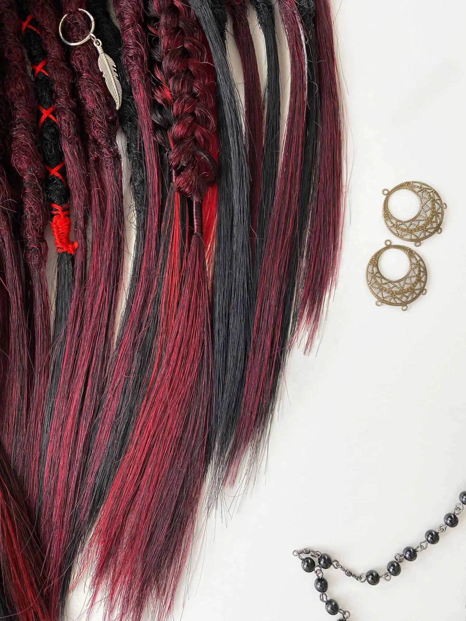 Bloodmoon textured dread extensions top section — flat 3-strand thin braid and silver feather charm