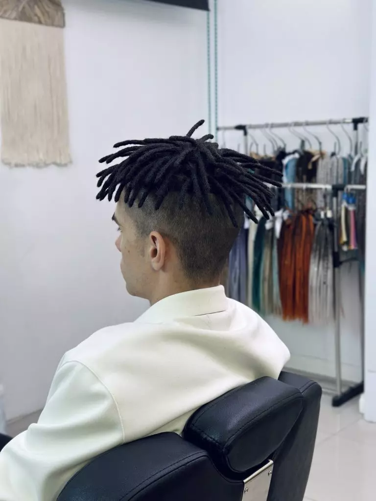 Short black natural dreadlocks with an undercut, side view
